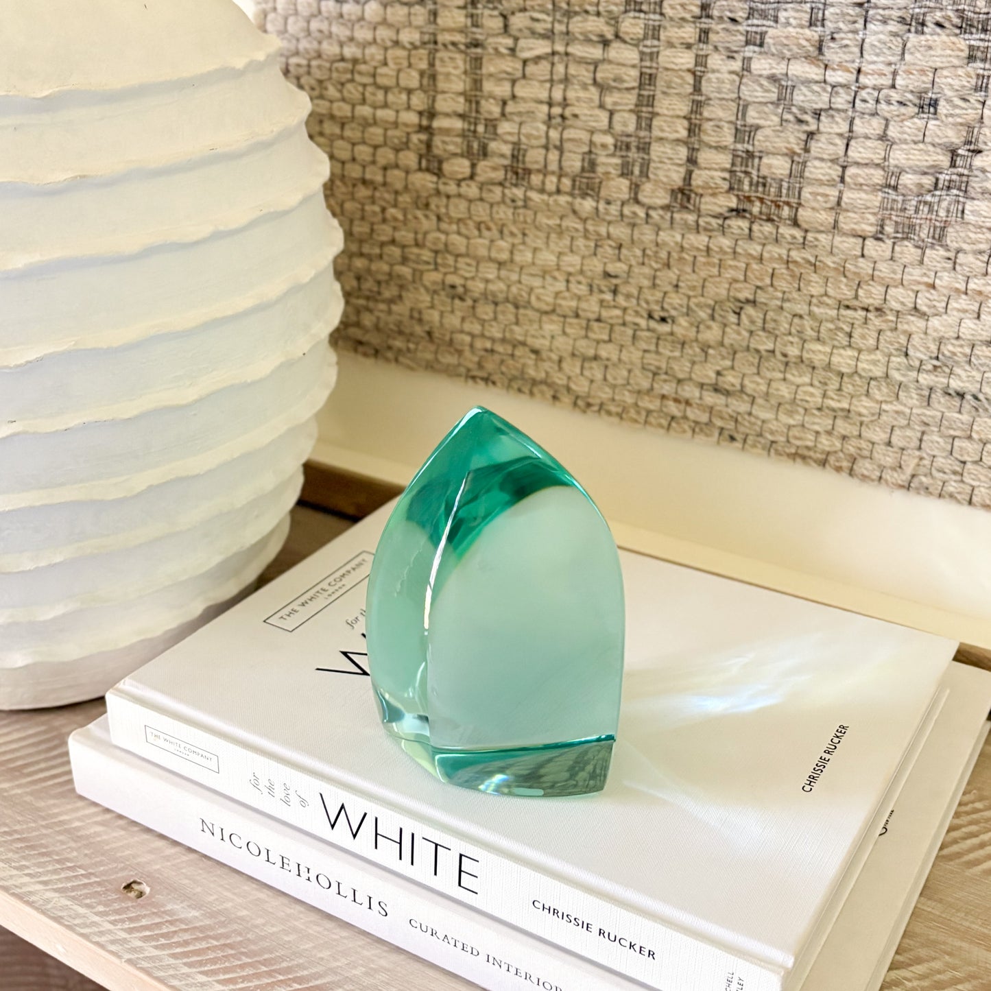 Teal glass art piece used as shelf decor in a modern, minimalist setting