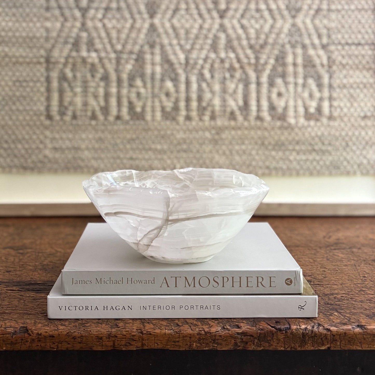 Decorative bowl on top of books with a textured wall in the background