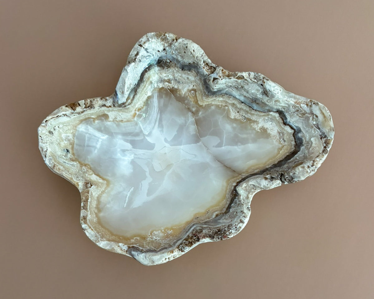 Decorative amber onyx bowl with distinctive natural banding and translucent honey-colored tones, hand-carved from solid stone