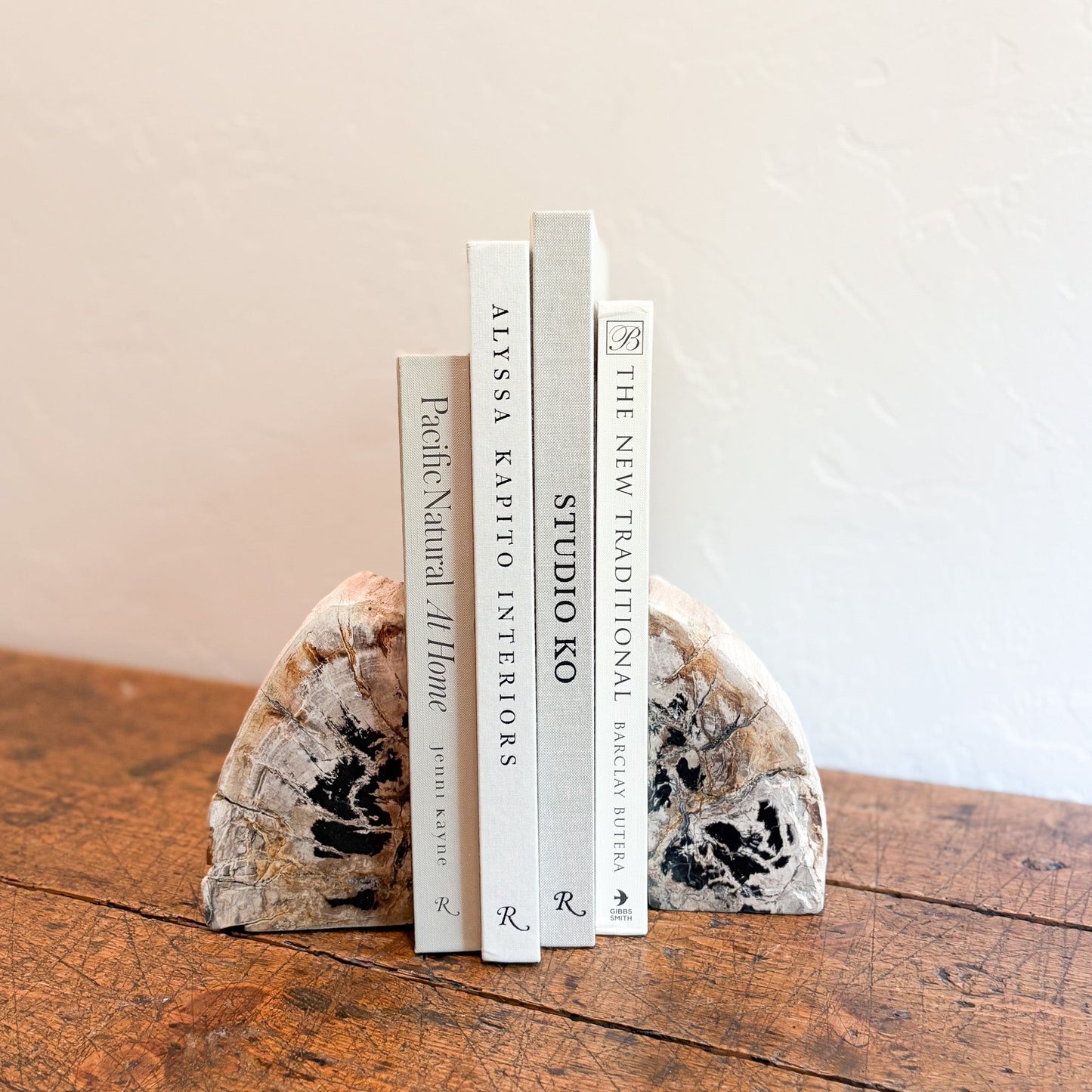 Decorative fossilized wood bookends with books on a wooden surface against a neutral background