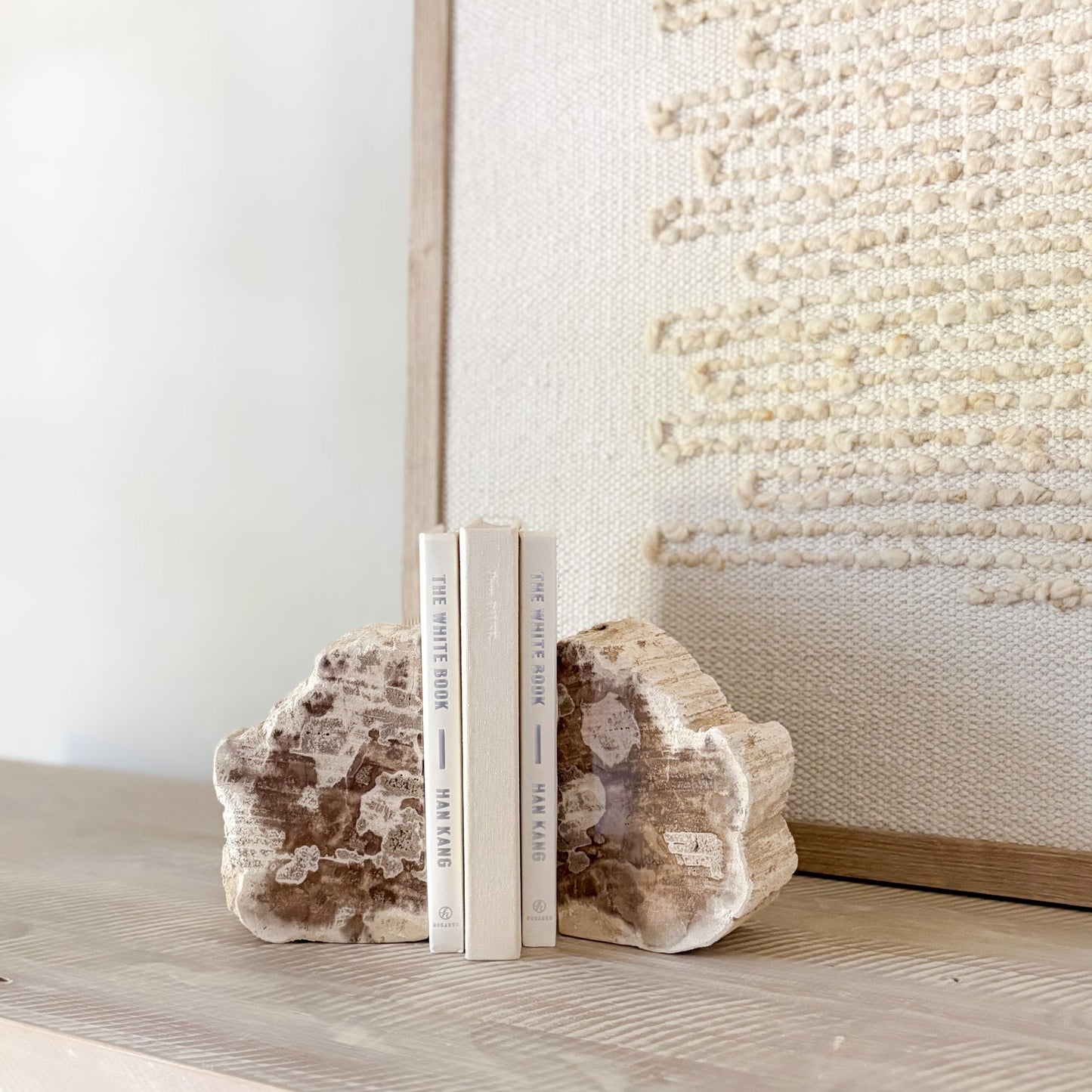 Two books between natural stone bookends on a surface with a textured wall in the background