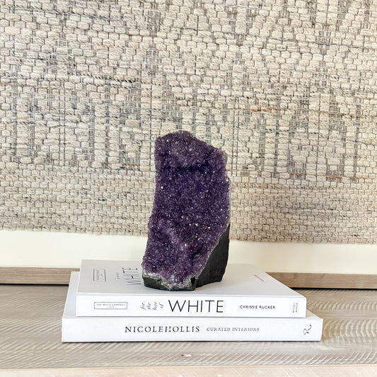 Purple amethyst crystal on top of books with a textured wall background