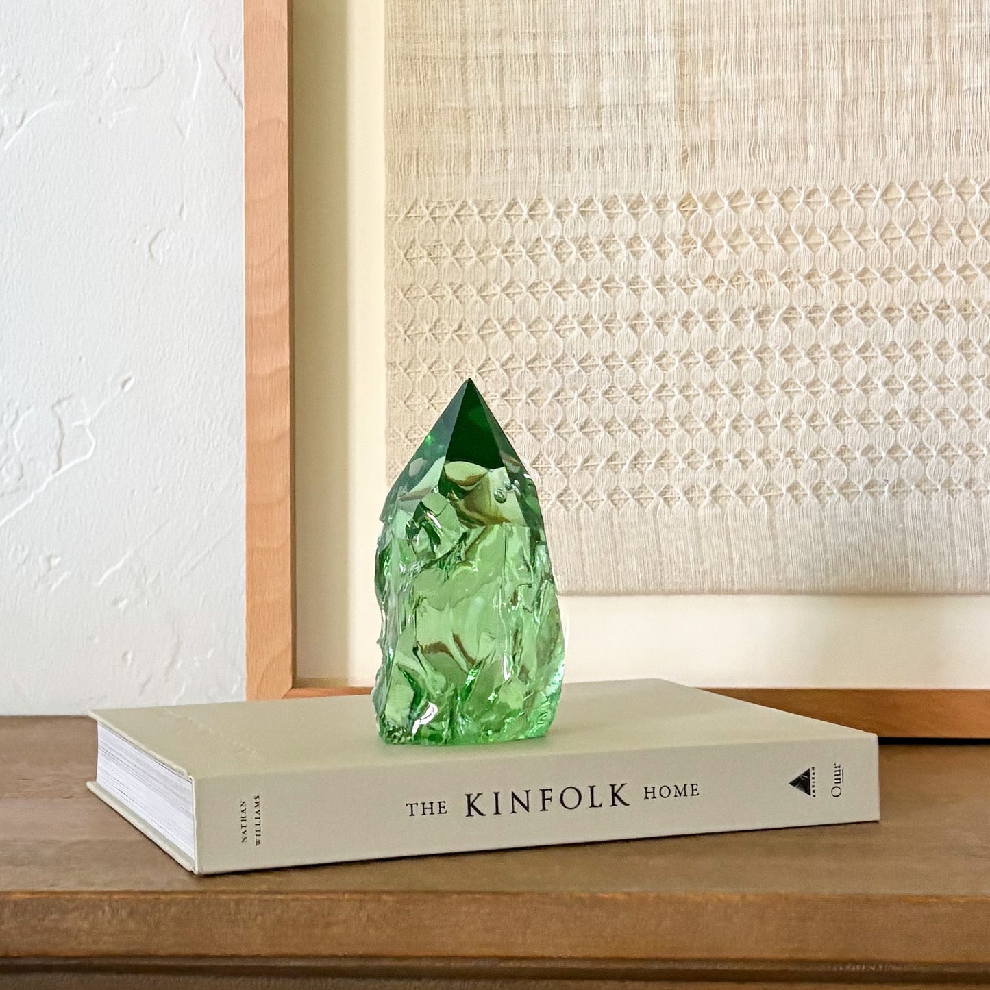 Artisan green glass crystal point with textured finish, styled in minimalist home decor scene