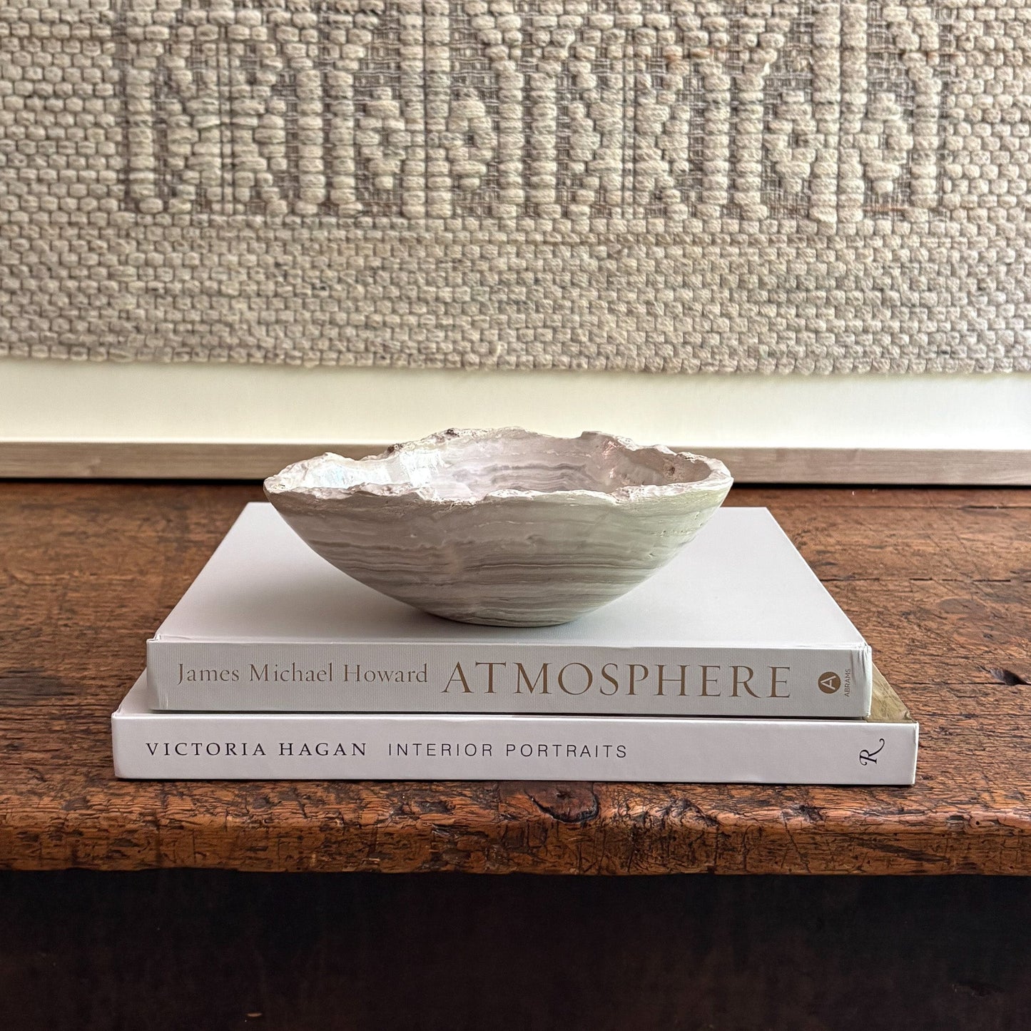Decorative bowl on top of two books with a textured wall in the background