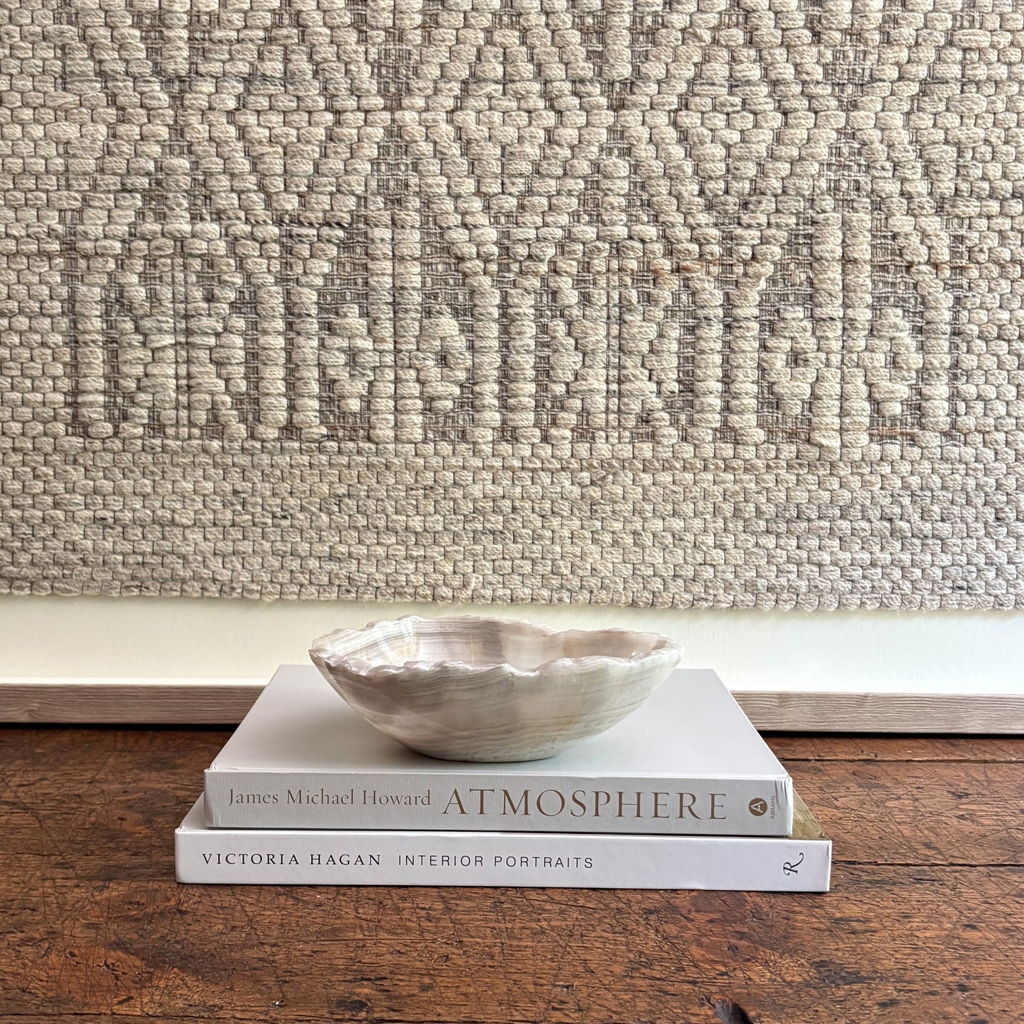 Stack of books with a decorative bowl on a textured wall background