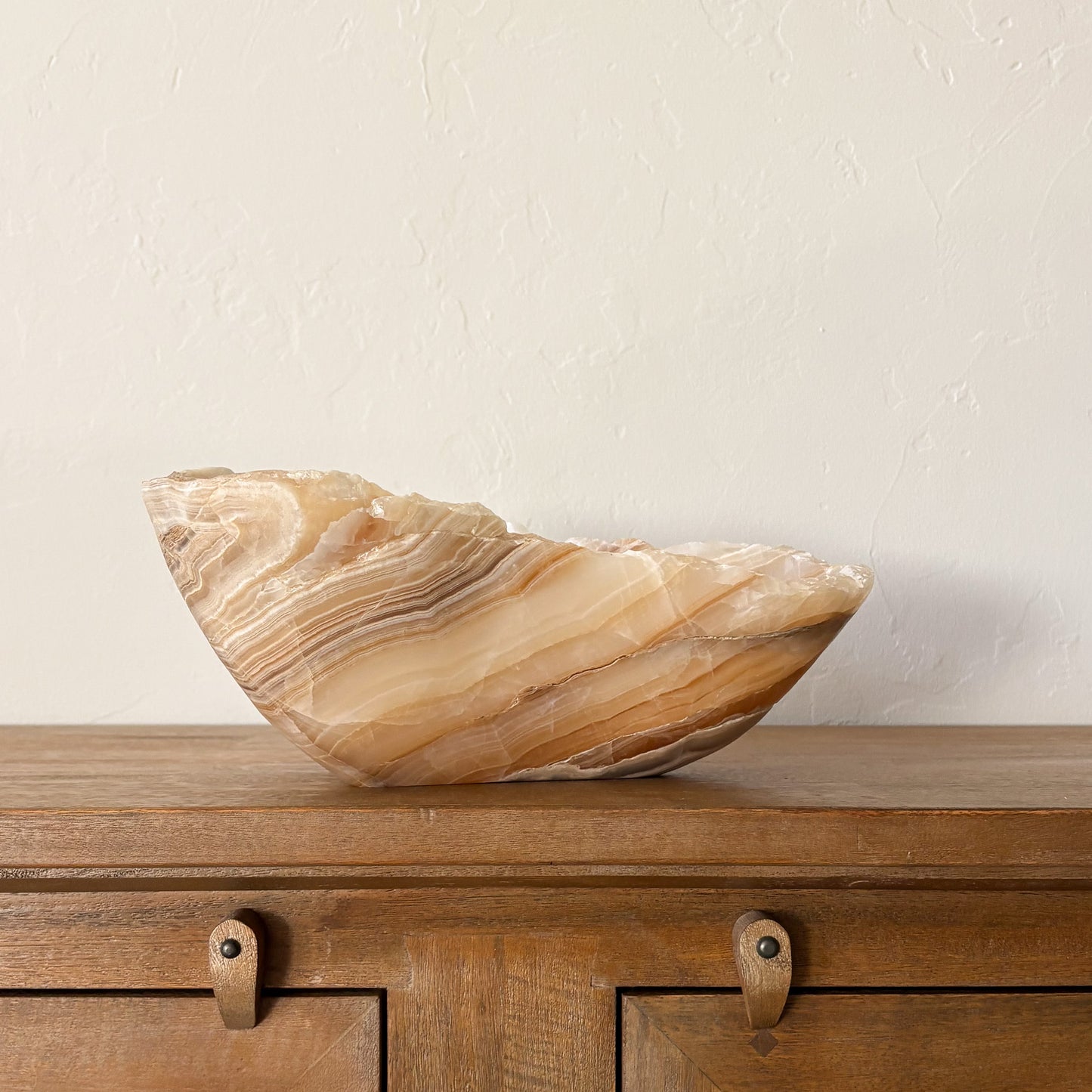 Luxury large amber onyx bowl displayed on mid century wooden cabinet