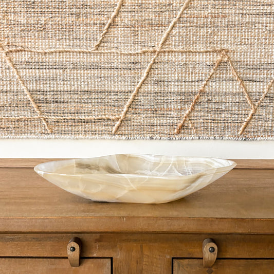 Large hand carved amber onyx bowl with organic shape on wooden table