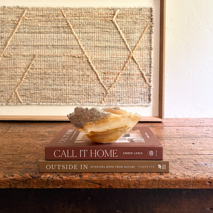 Decorative onyx stone bowl on books with a textured wall in the background