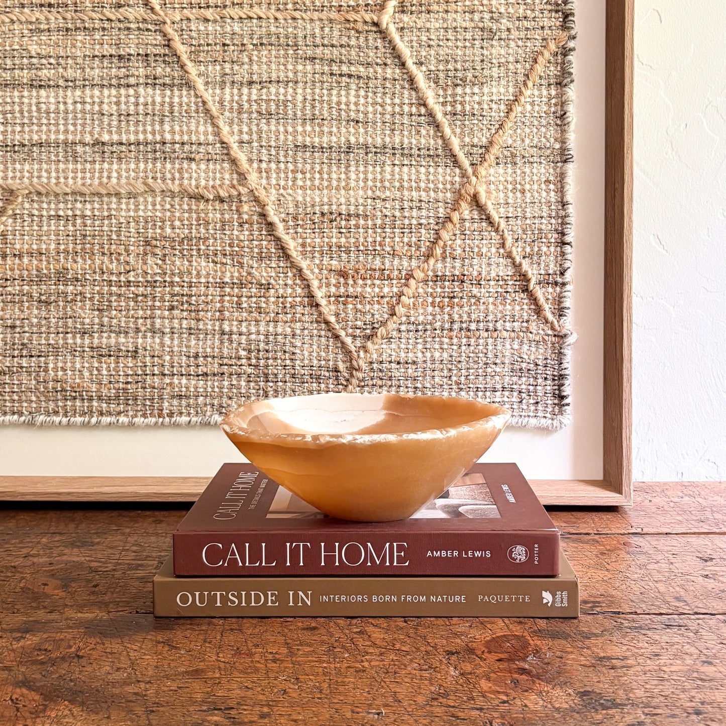 Decorative onyx bowl on books with a textured wall in the background