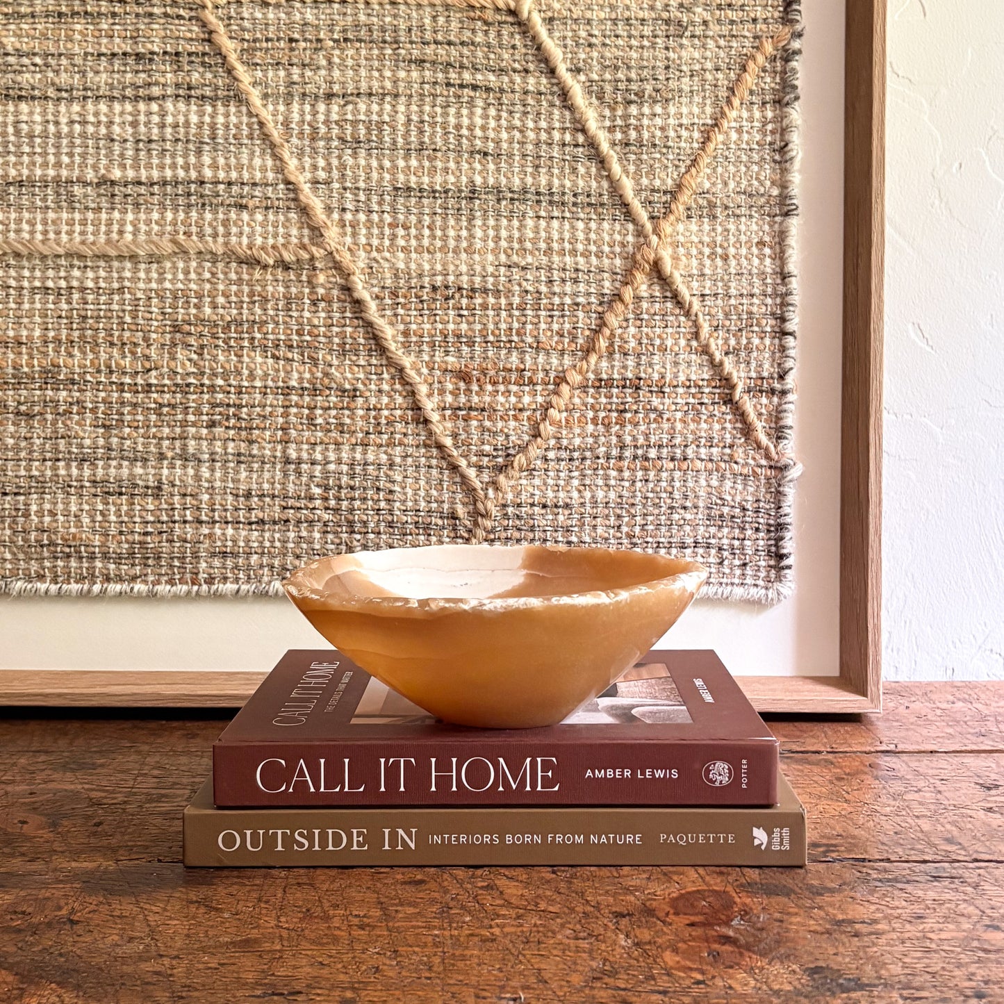 Brown onyx bowl on two books with a textured wall in the background