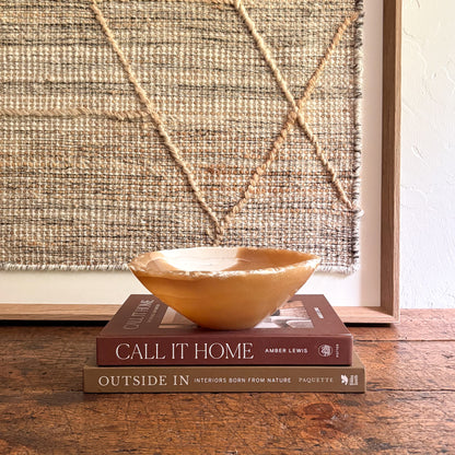 Brown onyx bowl on two books with a textured wall in the background