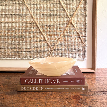 Decorative onyx bowl on top of two books with a textured wall in the background