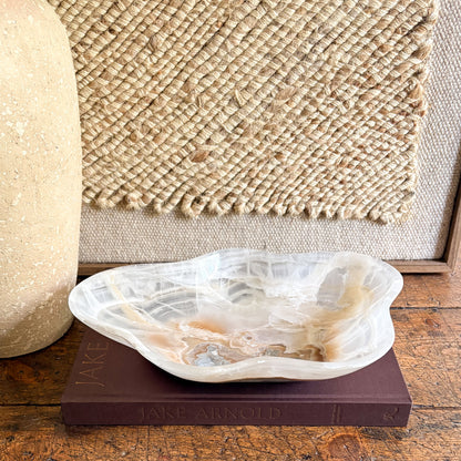 Decorative  onyx bowl on a book with a textured wall in the background