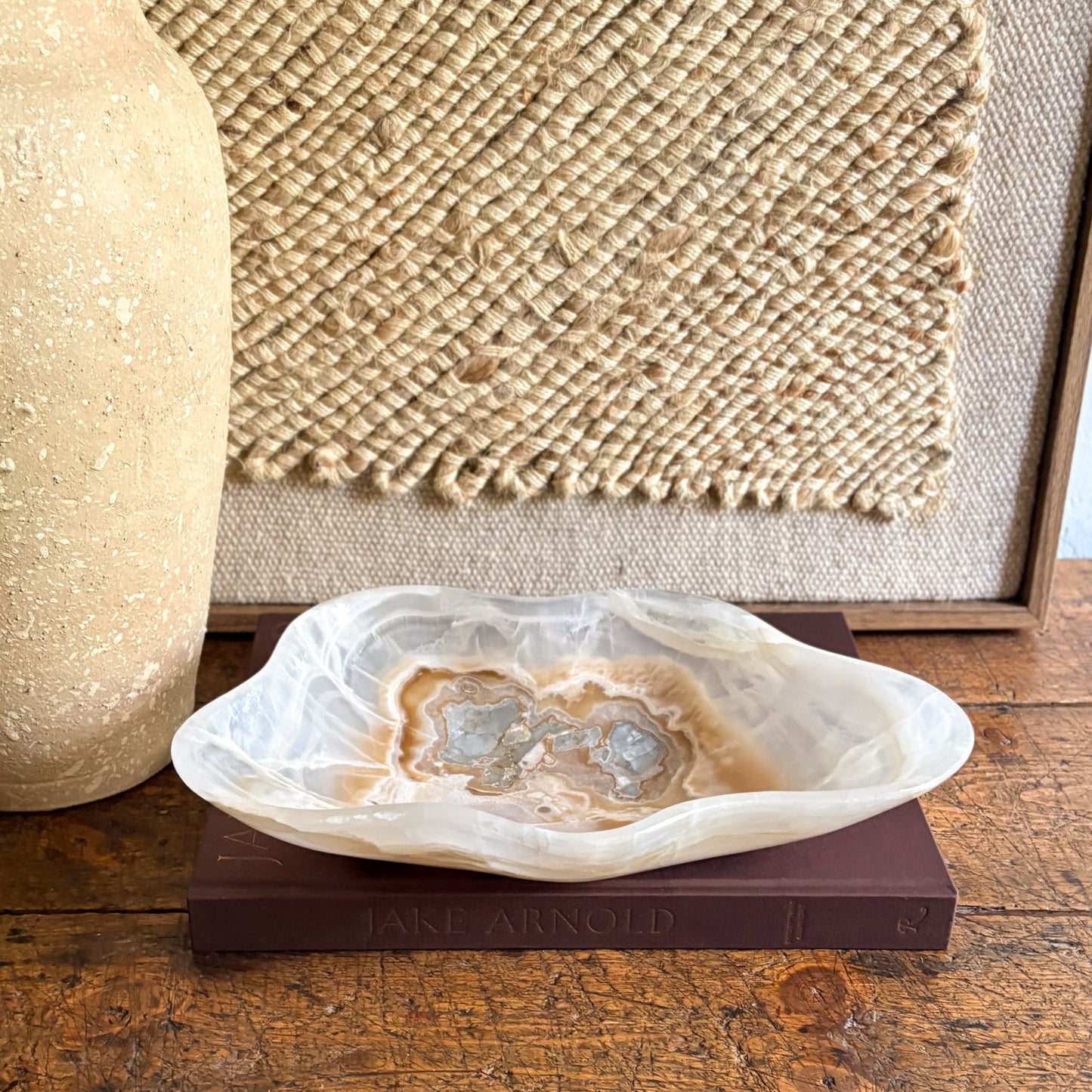 Decorative brown and white stone bowl on a book with a textured wall in the background
