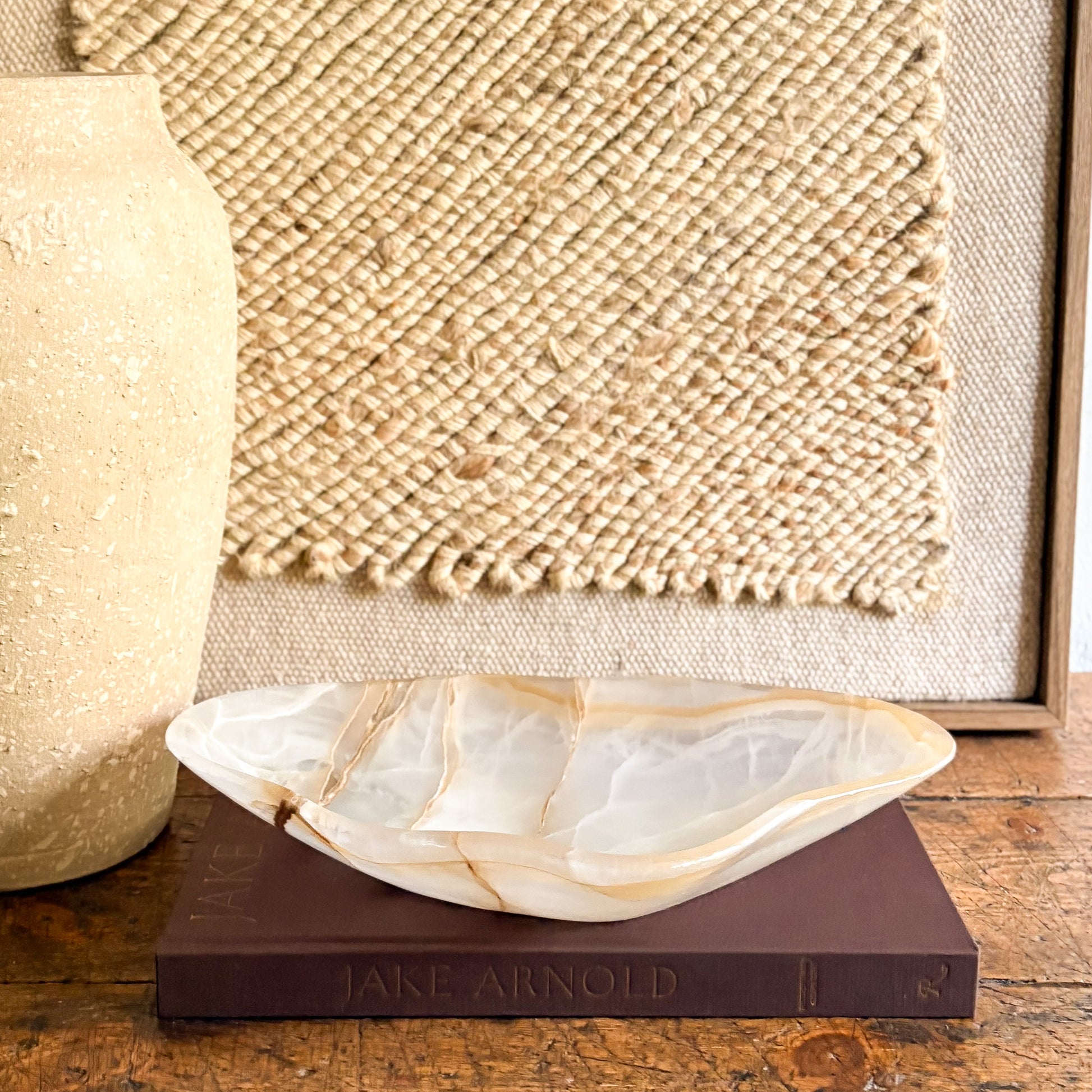 Decorative natural stone bowl on a book with a textured wall in the background