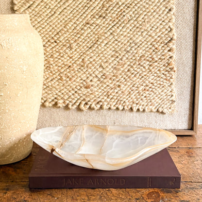 Decorative natural stone bowl on a book with a textured wall in the background