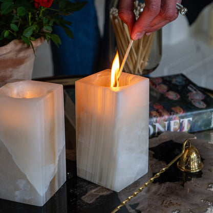 Hand lighting an amber onyx tealight candle holder with warm ambient candle glow