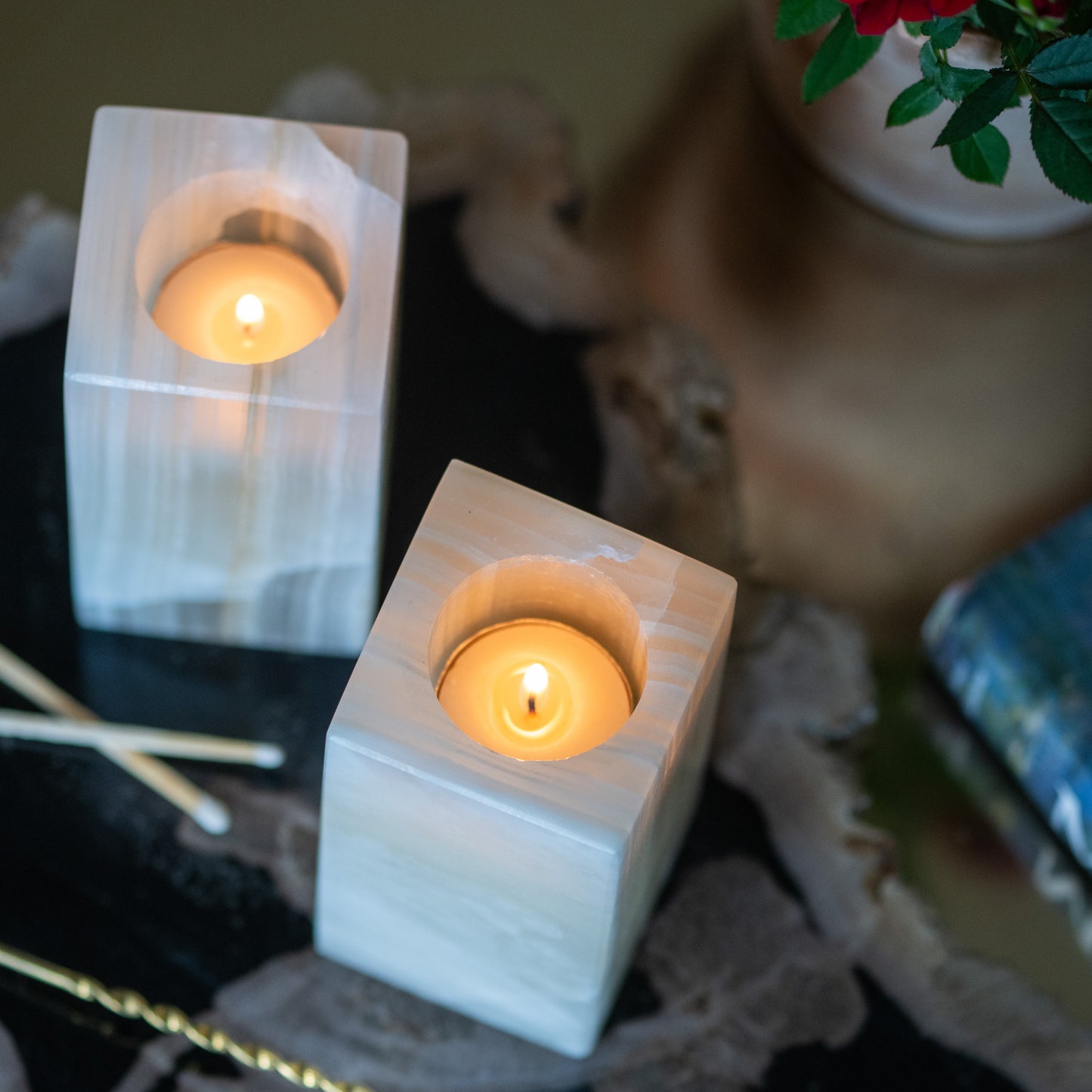 Top view of amber onyx tealight candle holders styled on a gold side table with red roses and decorative accents