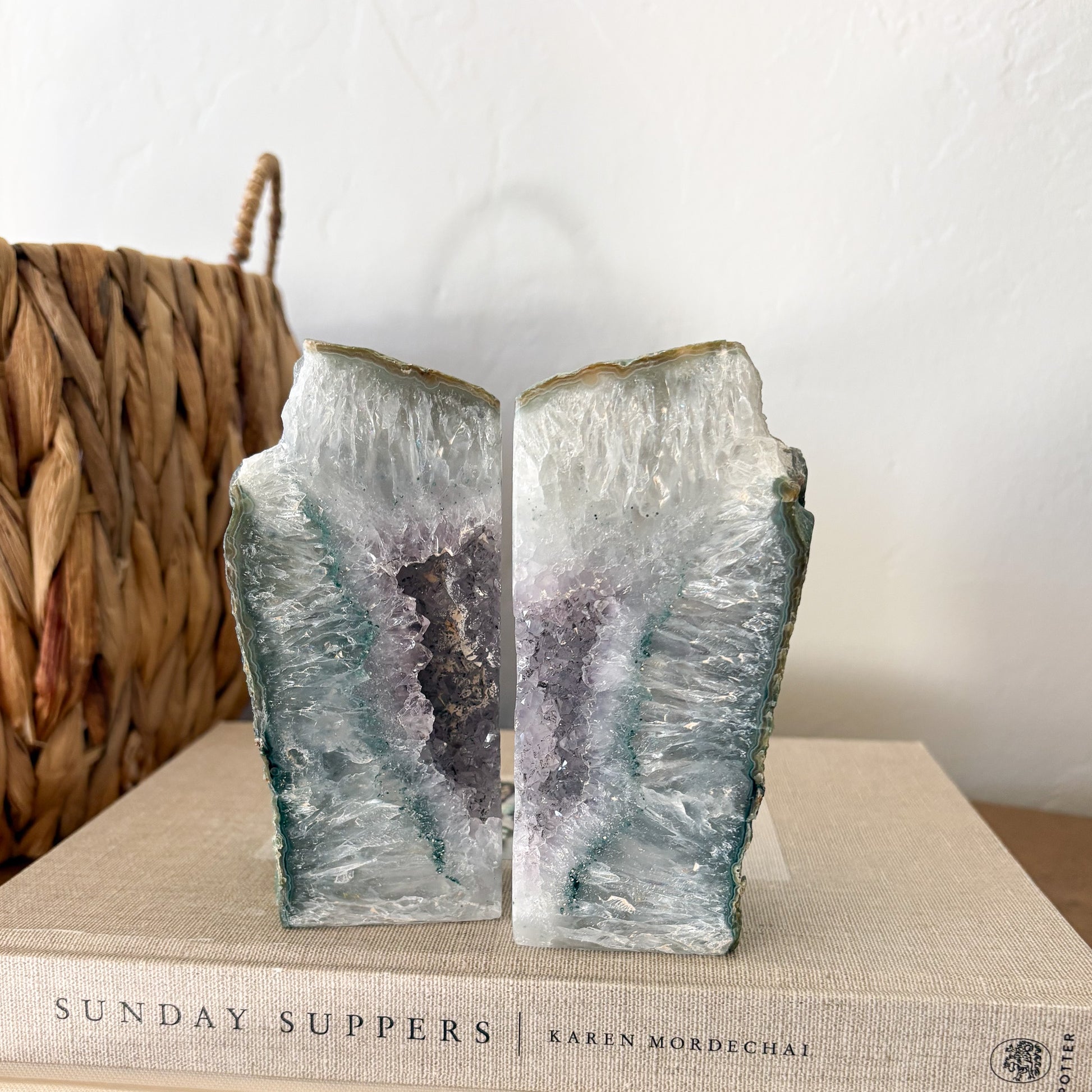 Brazilian agate geode bookend pair with pale green banded edges and lavender quartz crystal center on neutral decor book