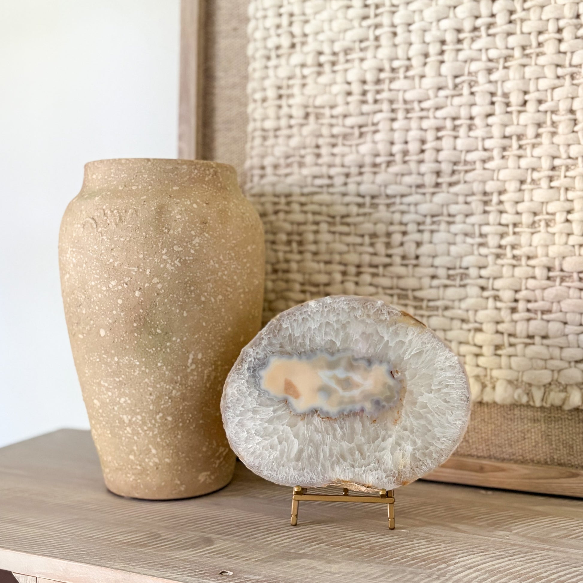 Beige textured vase and agate slab on a wooden surface with a woven basket in the background