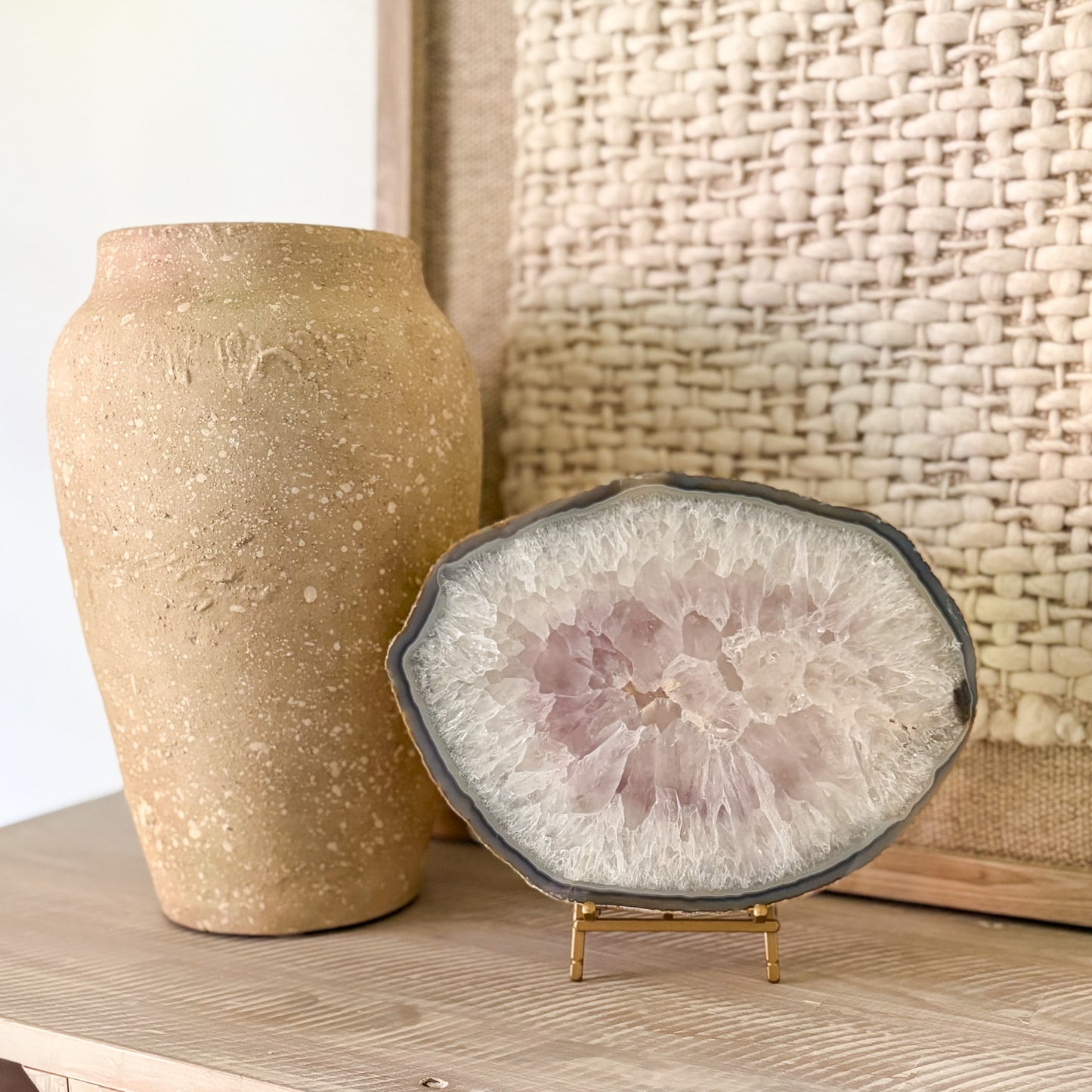 Decorative agate stone slice on a stand next to a textured vase against a woven basket background