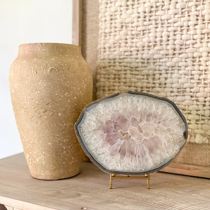 Decorative agate stone slice on a stand next to a textured vase against a woven basket background