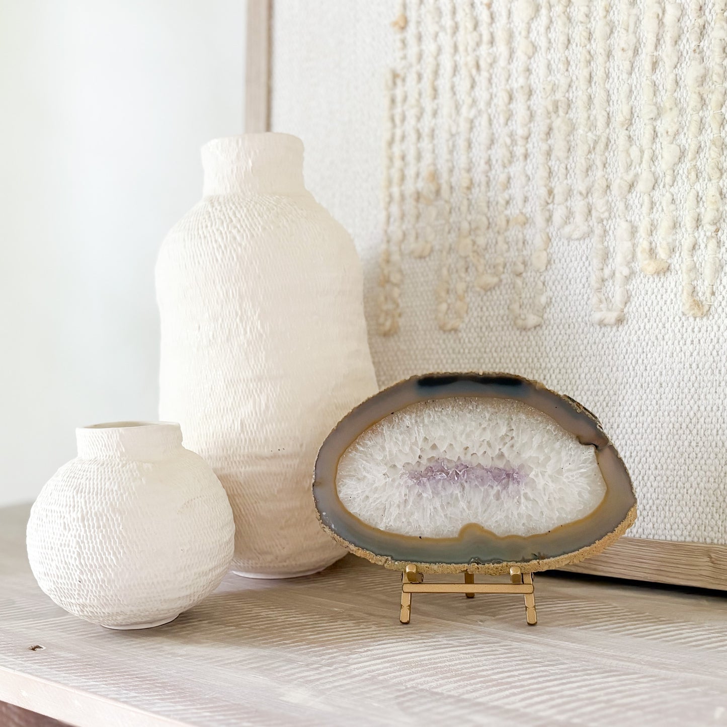 Two textured vases and an agate geode slice on a wooden surface with a neutral background