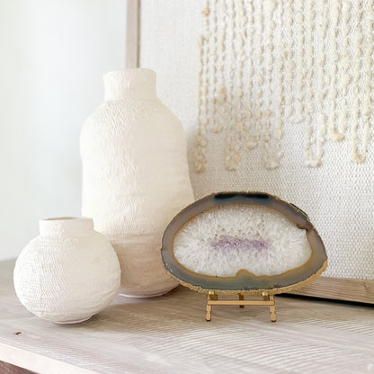 Two textured vases and an agate geode slice on a wooden surface with a neutral background
