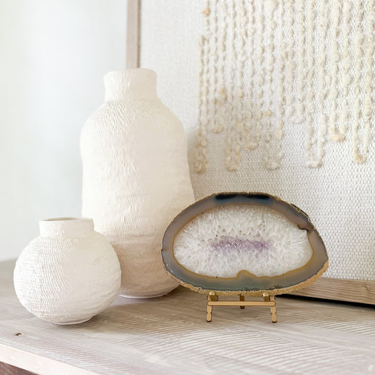 Two textured vases and an agate geode slice on a wooden surface with a neutral background