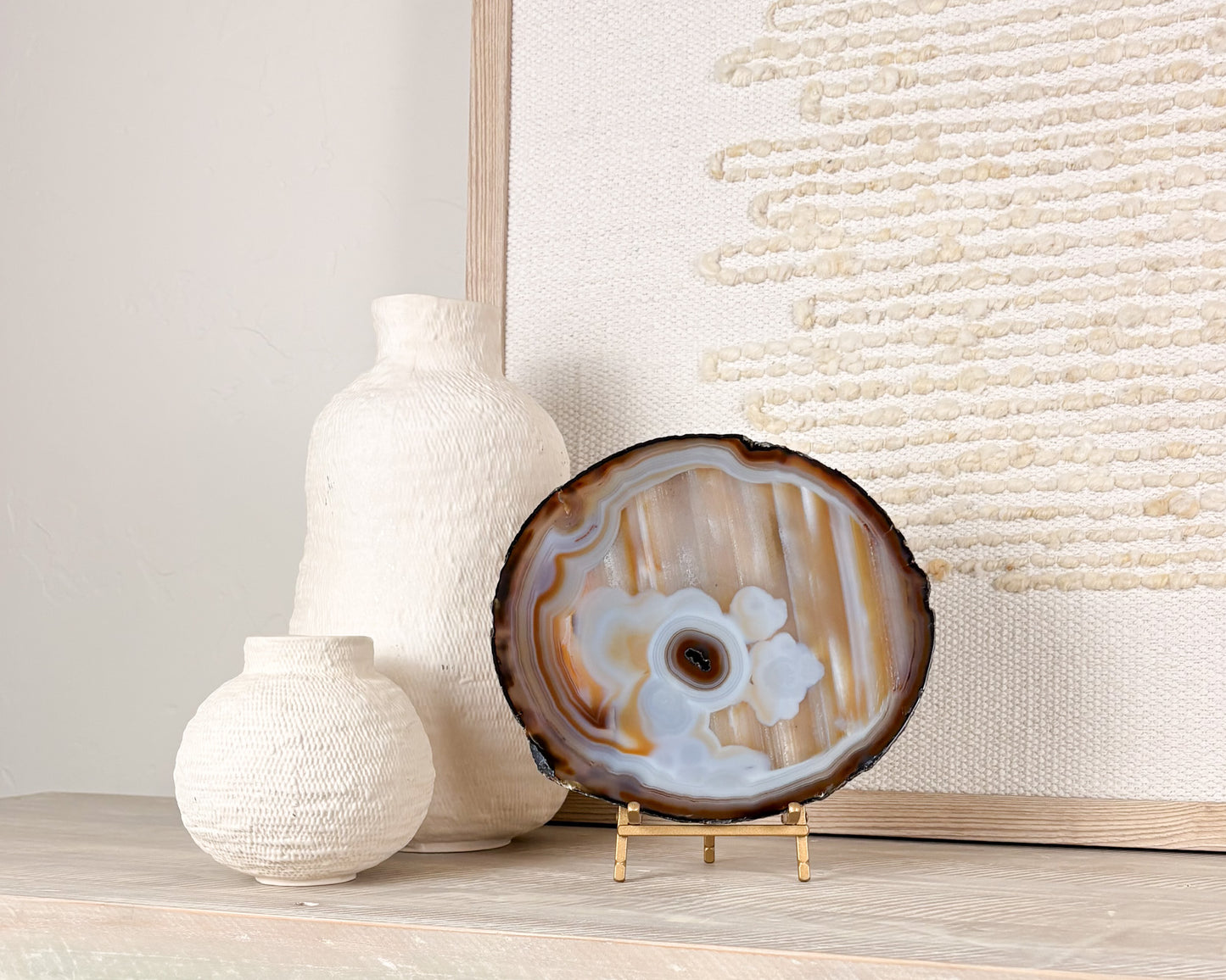 Polished Brazilian agate slice with natural crystal details displayed on a decorative stand