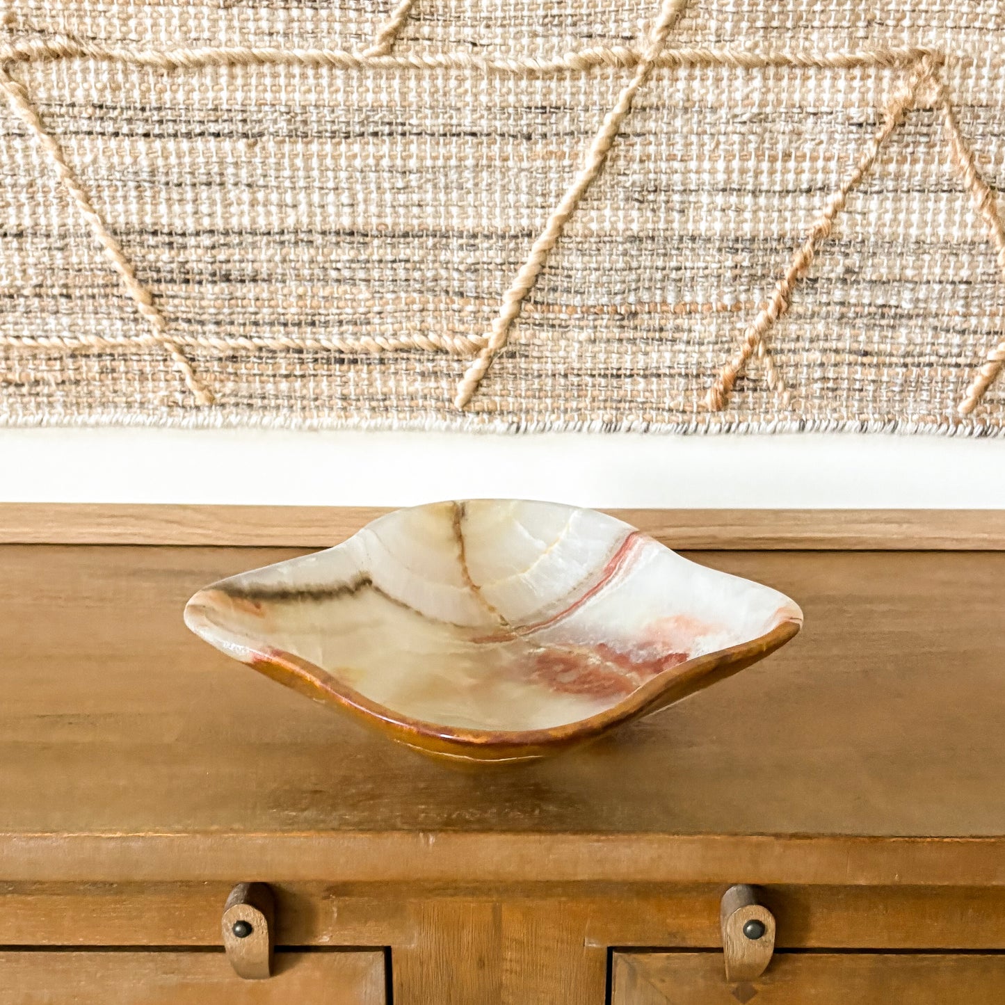 Elegant brown onyx bowl hand carved from natural stone, styled as a decorative centerpiece on a wooden sideboard