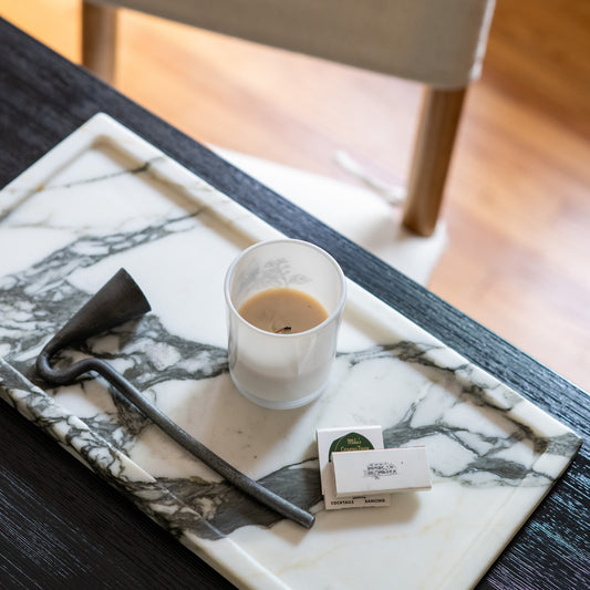 Calacatta Borghini marble tray styled with candle and matches on dark wood coffee table