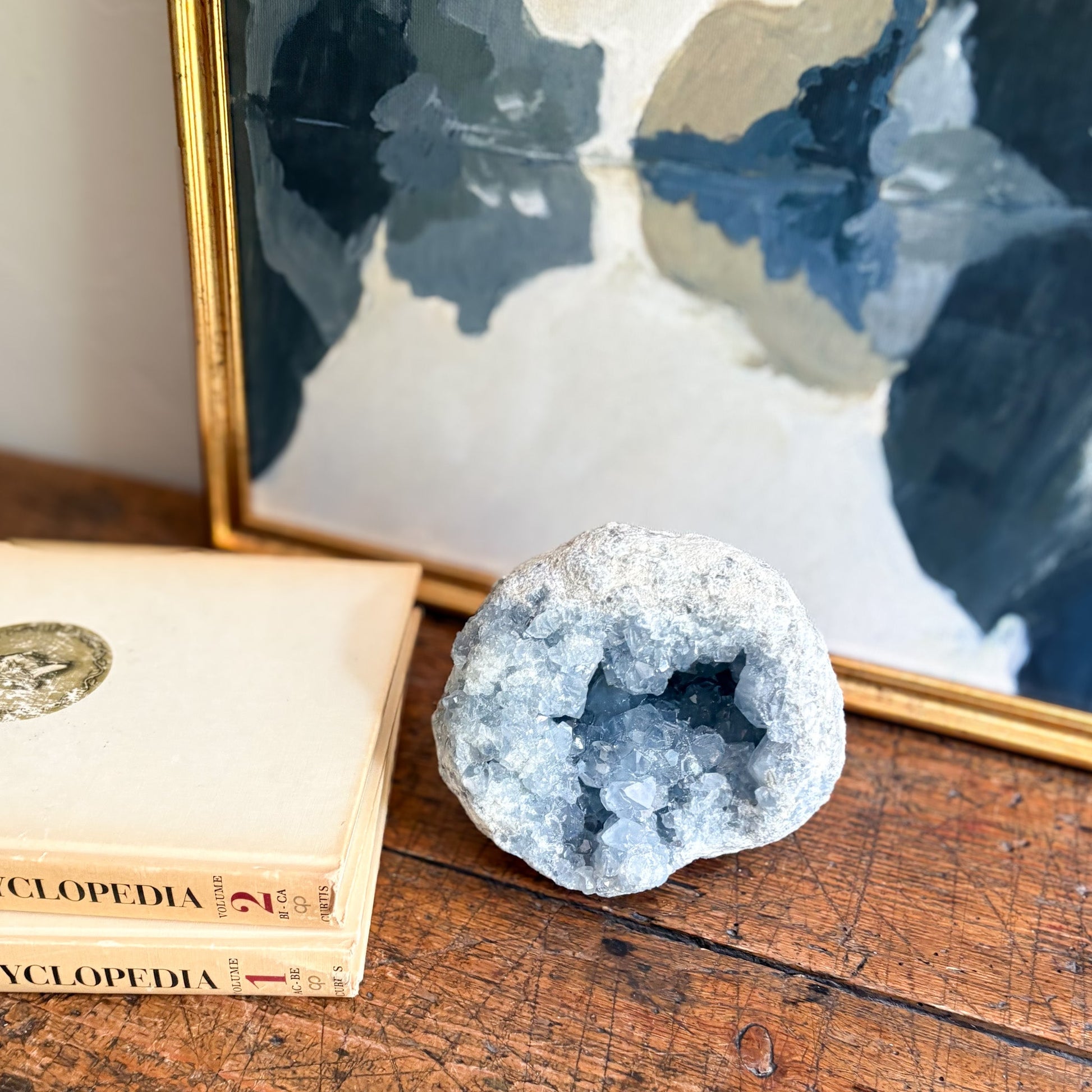 Geode crystal on a wooden surface with encyclopedias and a world map in the background
