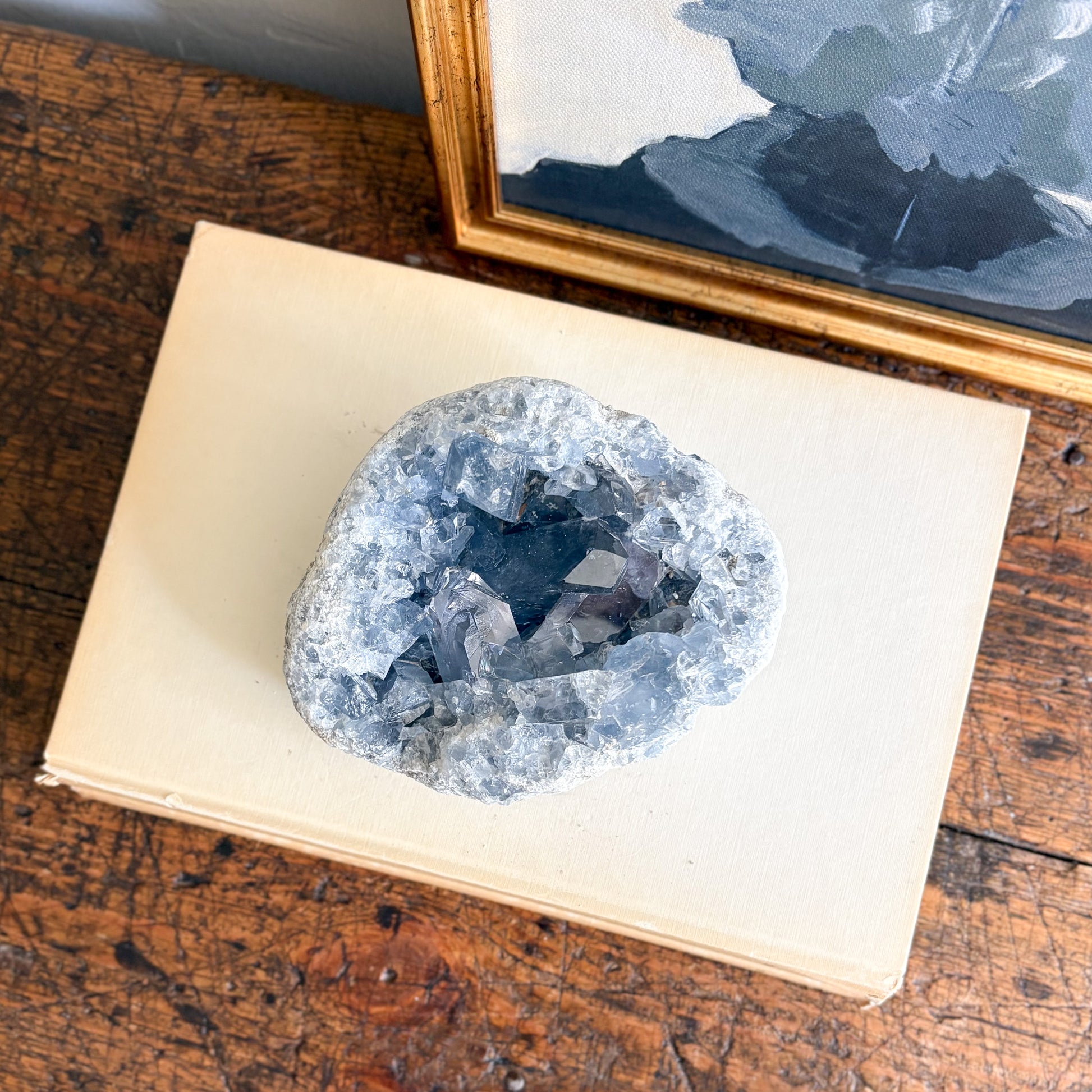 blue Geode crystal on an open book with a framed picture in the background