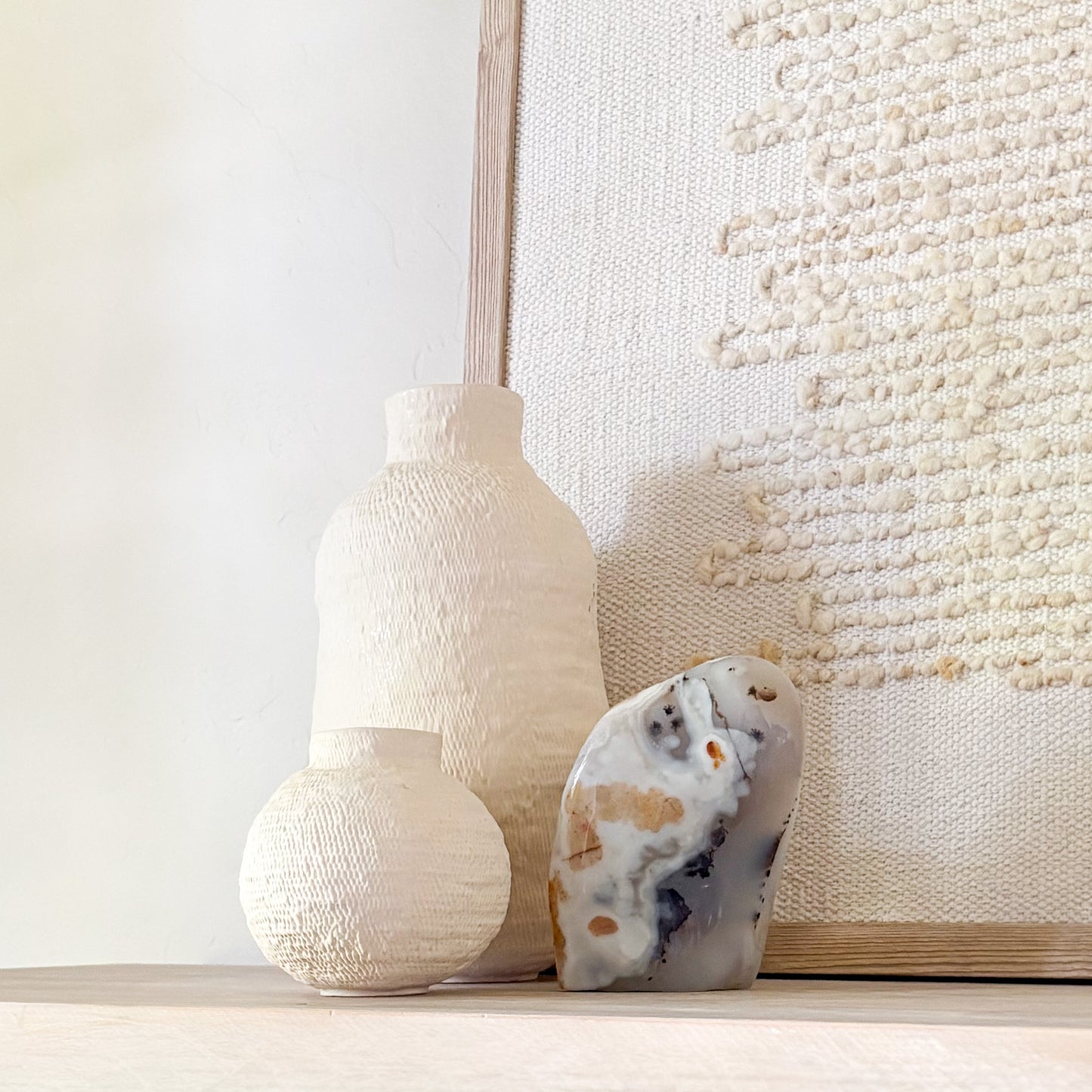 Fern agate sculpture styled with textured wall hanging and ceramic decor in neutral home