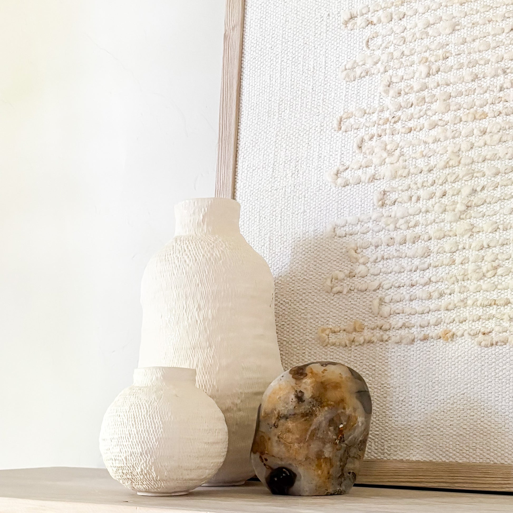 Fern agate sculpture styled with textured wall hanging and ceramic decor in neutral home
