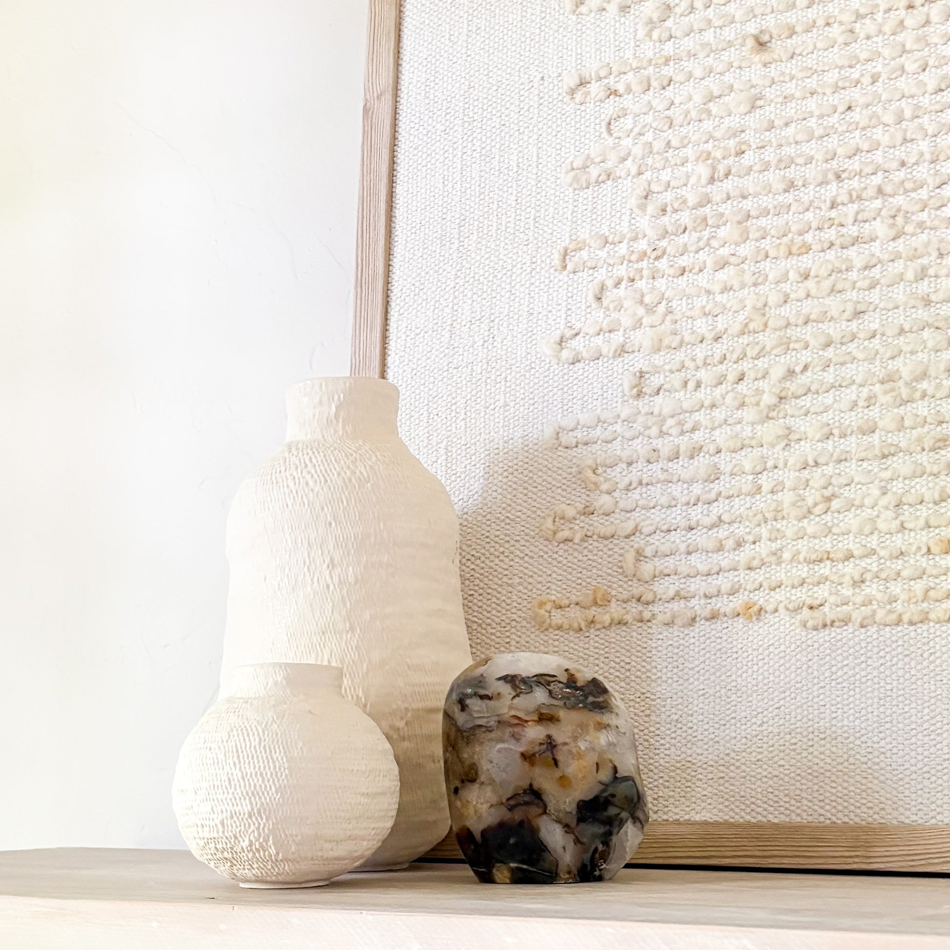 Organic modern shelf styling with natural stone sculpture and handcrafted ceramic vase