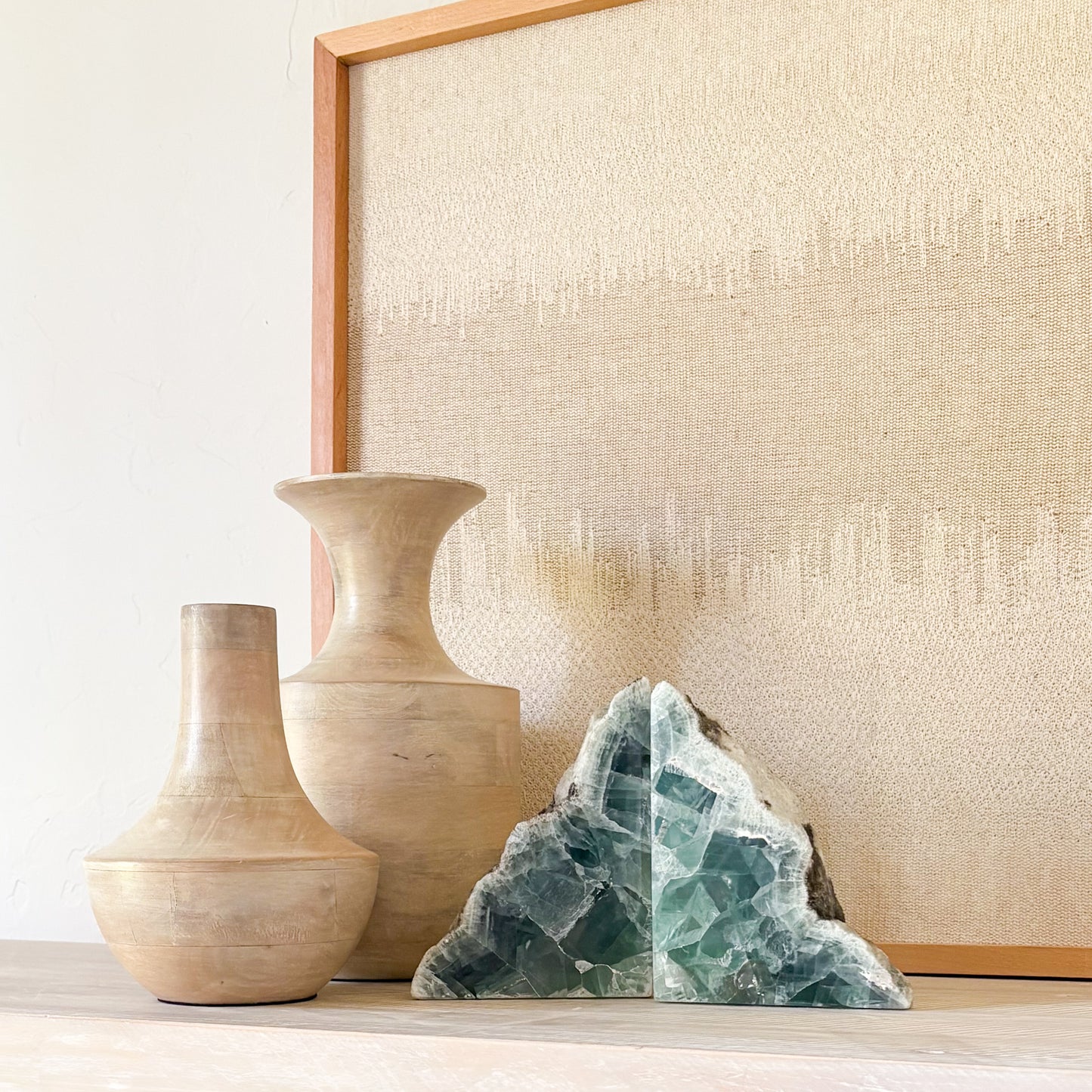 Green fluorite bookends displayed with sculptural vases in a luxury neutral interior