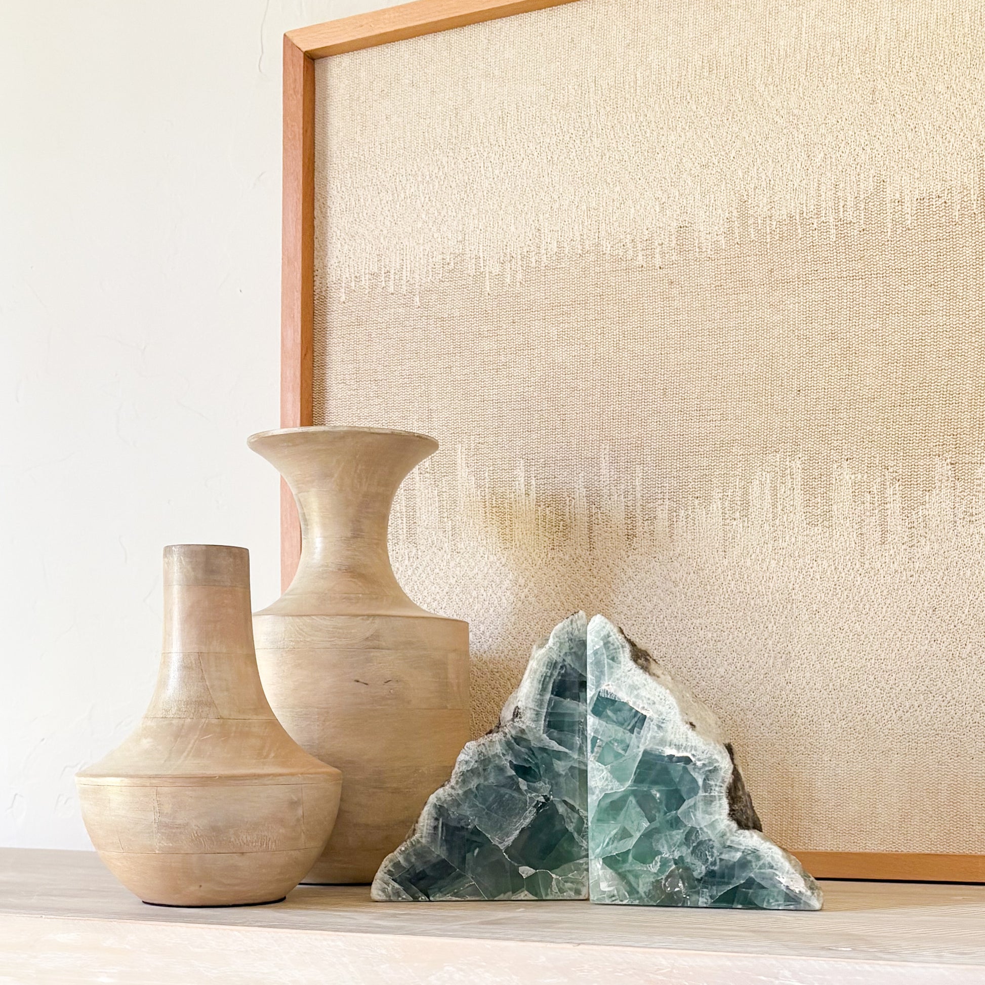 Green fluorite bookends displayed with sculptural vases in a luxury neutral interior