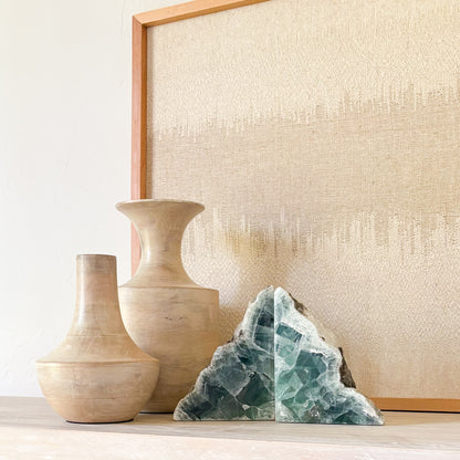 Green fluorite bookends displayed with sculptural vases in a luxury neutral interior