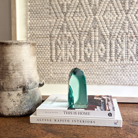 Decorative green crystal on books with a textured wall in the background
