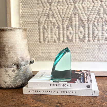Decorative glass piece on books with a textured wall in the background