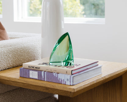 Modern green glass sculpture styled on a wooden side table
