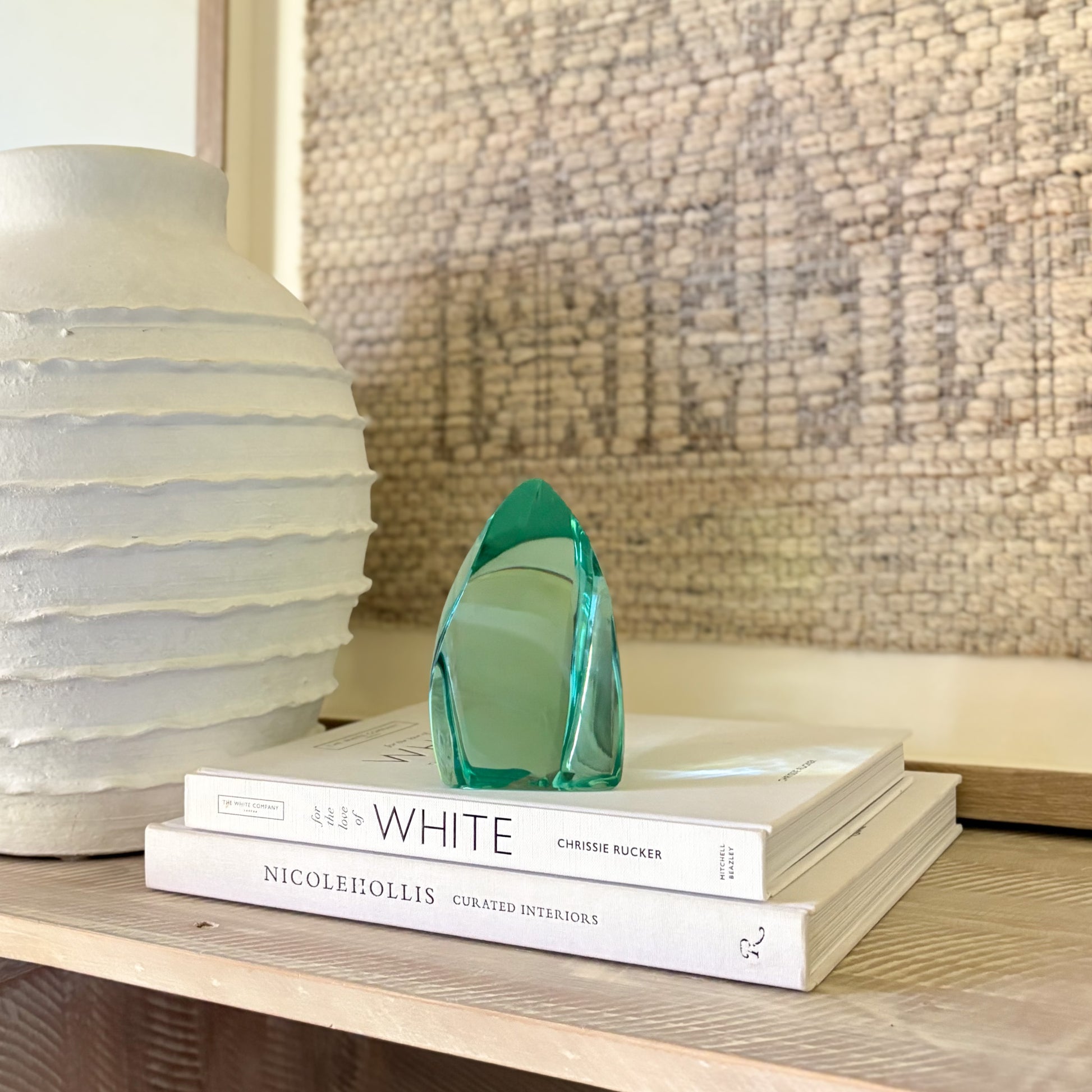 Green glass sculpture displayed on stacked design books