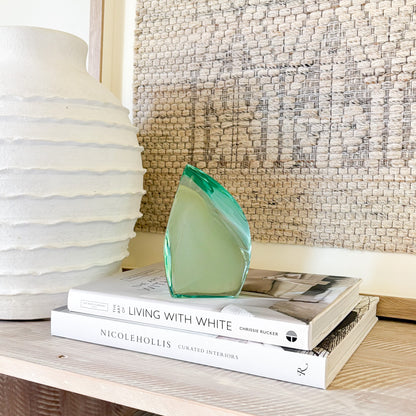 Green glass sculpture displayed on shelf in minimalist modern interior