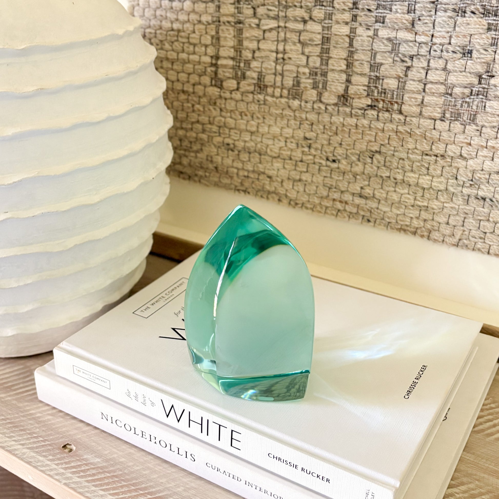 Teal glass art piece used as shelf decor in a modern, minimalist setting