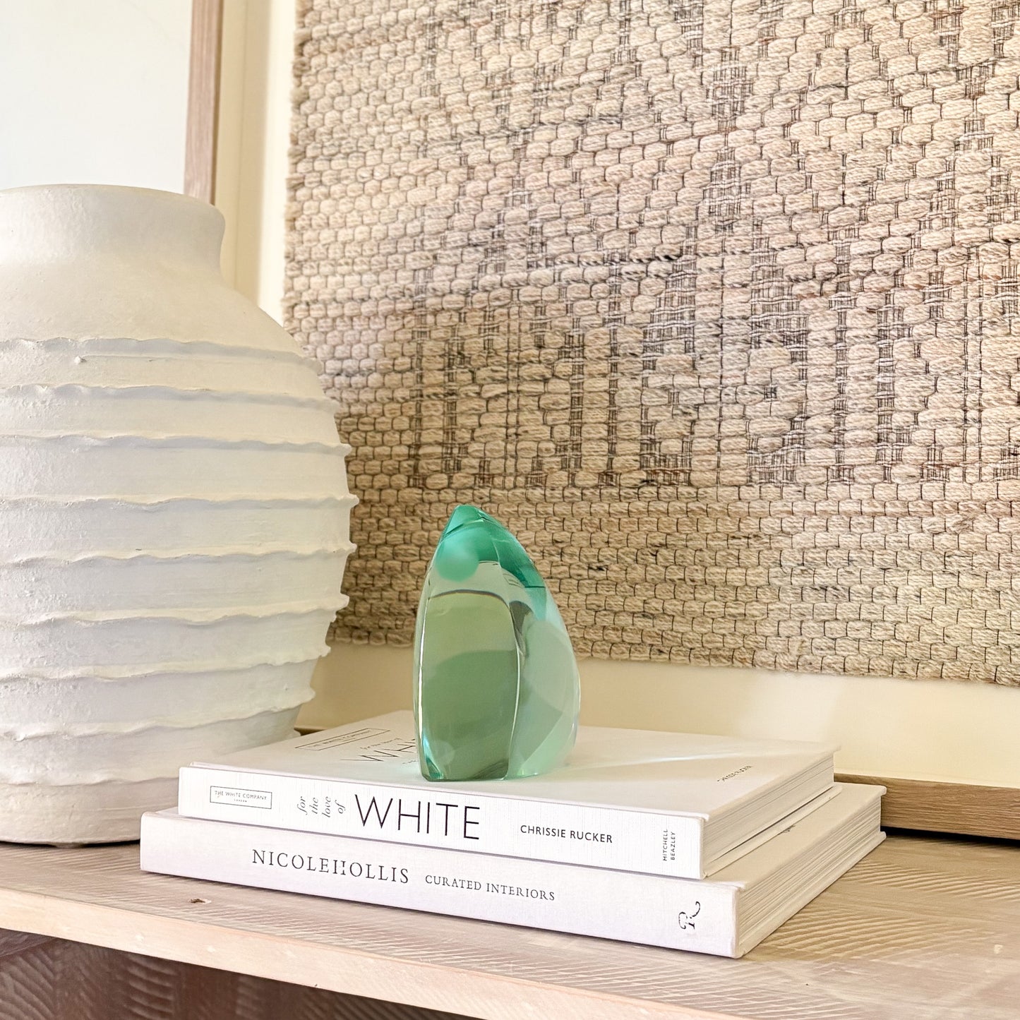 Abstract green glass sculpture with smooth, curved edges displayed on design books