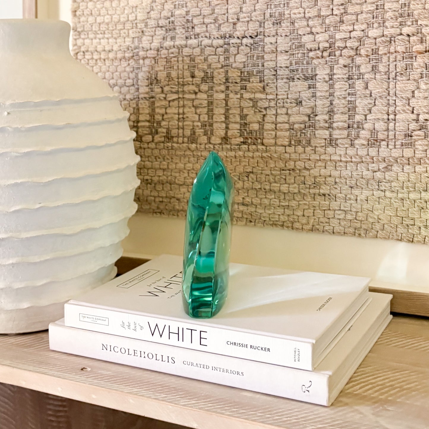 Teal glass art piece used as shelf decor in a modern, minimalist setting