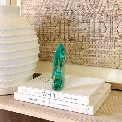 Teal glass art piece used as shelf decor in a modern, minimalist setting