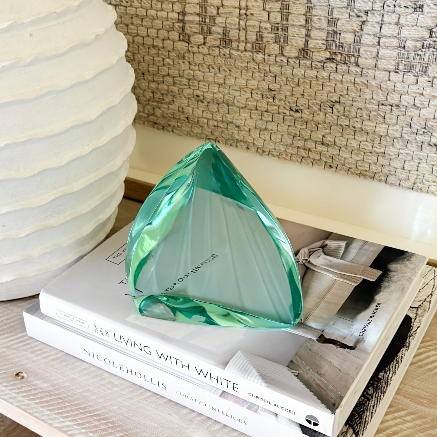 Green glass sculpture displayed on shelf in minimalist modern interior